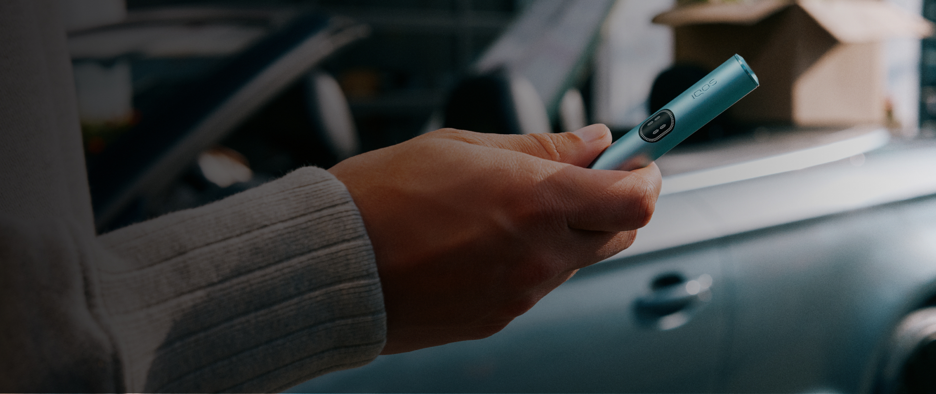 Persona sosteniendo Iluma i azul cerca de un automóvil con enfoque al dispositivo